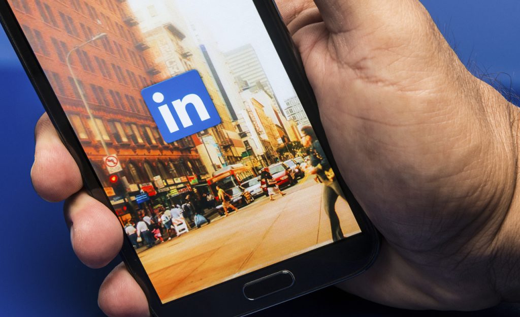 Hand holding a phone with LinkedIn open.