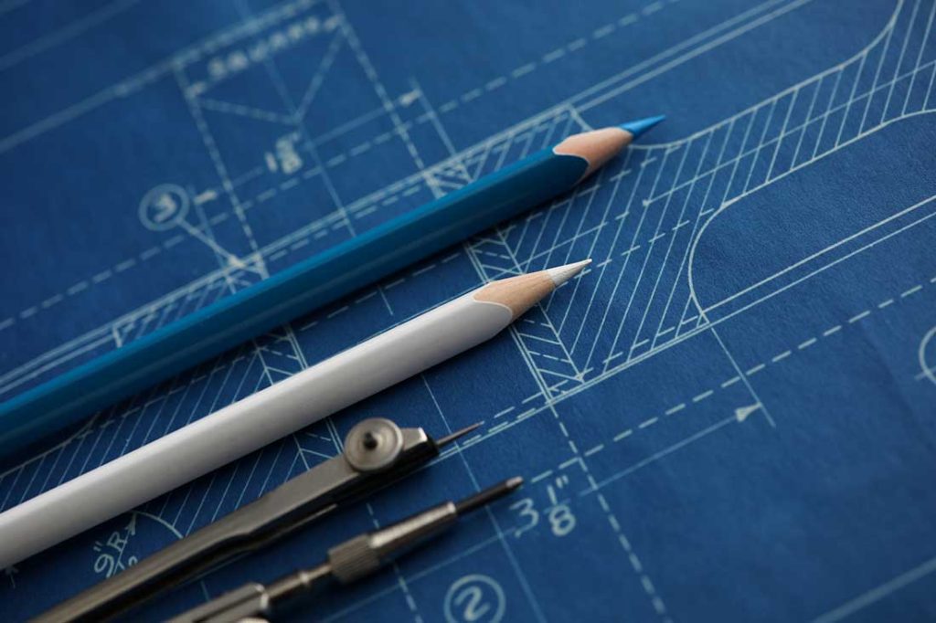 Pencils and a protractor lying on an architectural drawing.