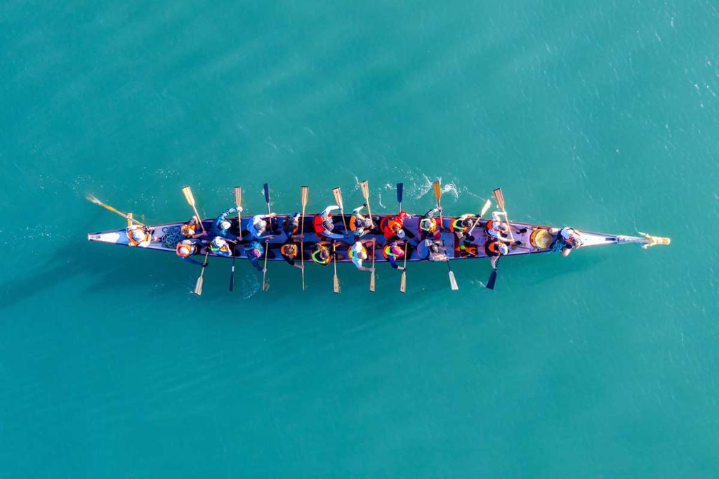 Team of people rowing a boat.