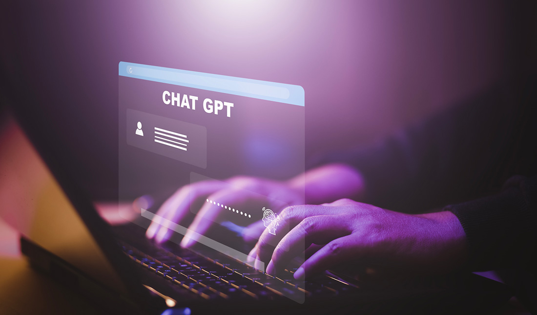 Person typing on a computer with Chat GPT's interface displayed on the screen.