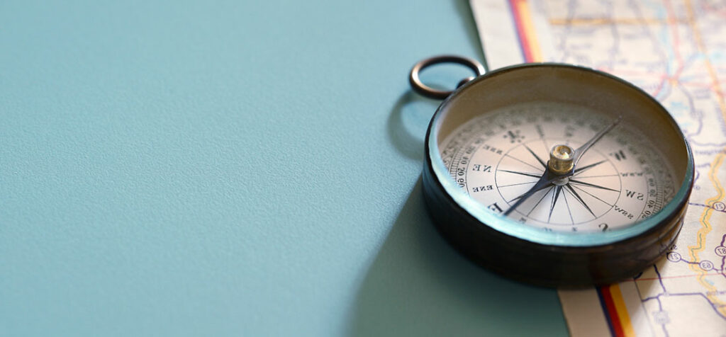 A compass lying on top of a map.