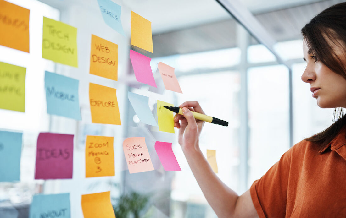 Person organizing various sticky notes on a wall.